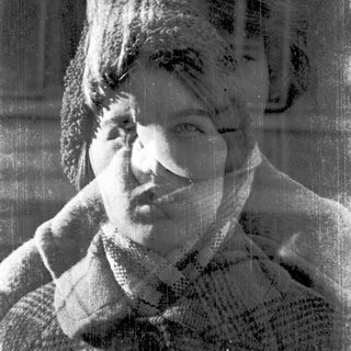 Blurred black-and-white portrait of a person scratching their neck.