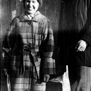 Two people posing outside an institution in winter attire.