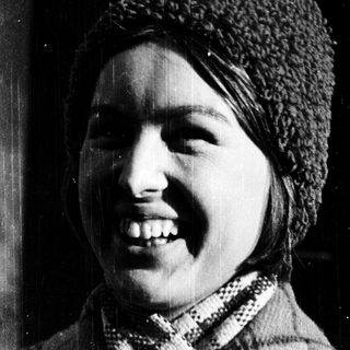 Smiling person wearing knit hat and scarf.