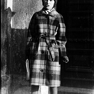 Young person wearing plaid coat and knit hat.