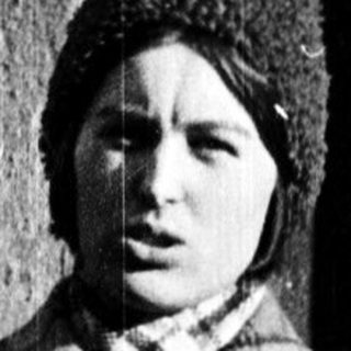 Young person wearing plaid coat and knit hat.