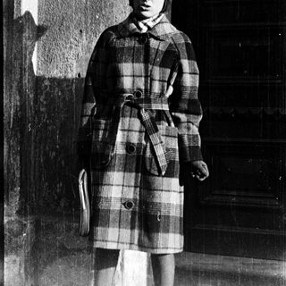 Young person wearing plaid coat and knit hat.