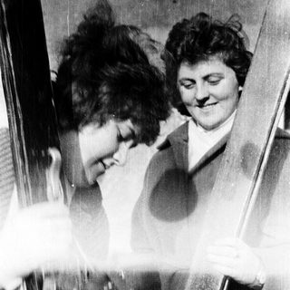 Two women laughing in a mirror.