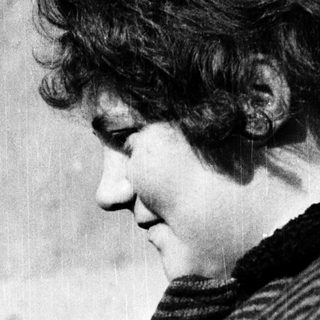 Woman with curly hair looking downward intently.
