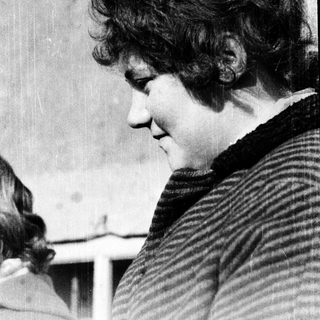Woman with curly hair looking downward intently.