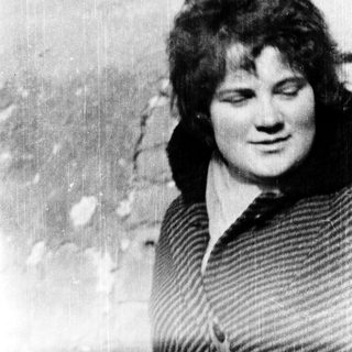 Young woman with short hair, smiling slightly.