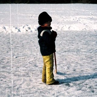 Child standing alone in snowy field at night.