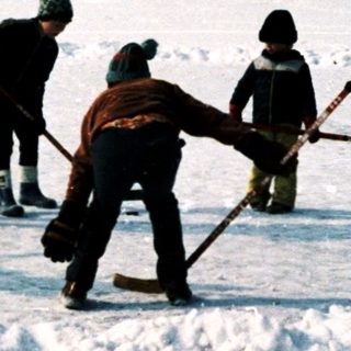 Children playing ice hockey on a snow-covered field.