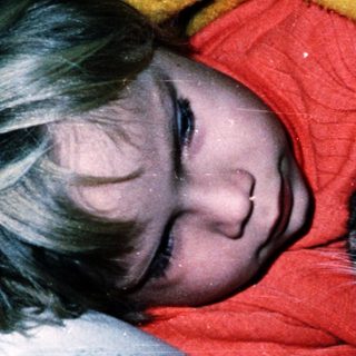 A person and a kitten resting together on a bed.