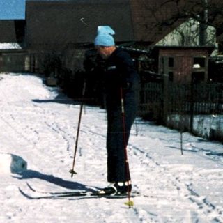 People skiing on snow-covered road.