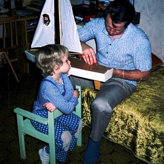 Man and child assembling a model sailboat together.