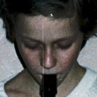 Child playing recorder in pajamas on a bed.
