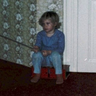 Child playing with toy on red carpet.