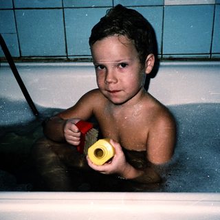 Young boy playing in a bathtub with toy.