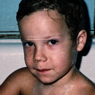 Young boy playing in a bathtub with toy.