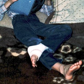 Boy reading book on couch with legs stretched out.
