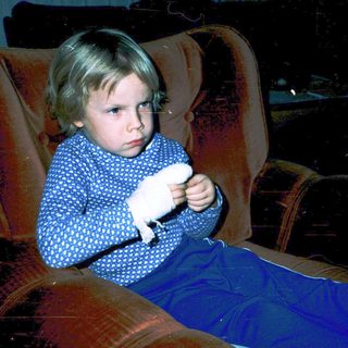 Child holding stuffed animal in movie theater seat.