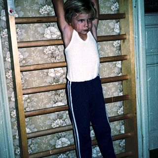 Young boy doing pull-ups on wooden ladder.