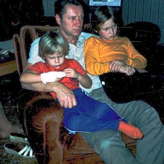 Family gathered indoors watching television in dim lighting.