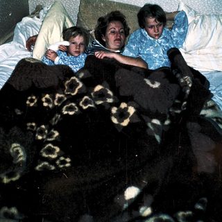 Family resting together on a bed.