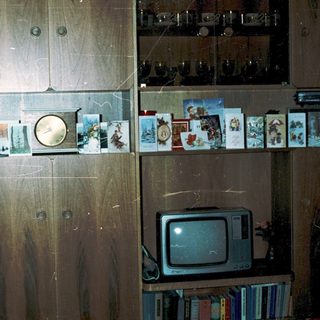 Vintage wooden cabinet with old photos, cassette tapes, and CRT TV.