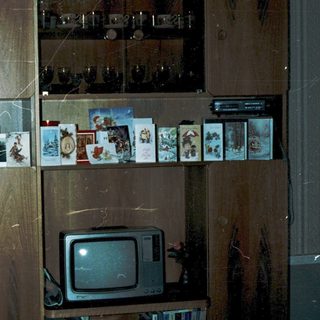 Vintage wooden cabinet with old photos, cassette tapes, and CRT TV.