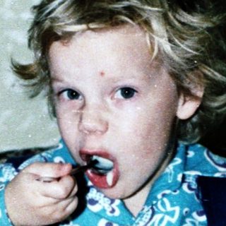 Child eating dessert with spoon indoors.