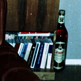 Child reading book on armchair in living room.