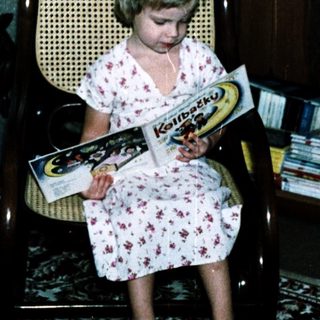 Young girl reading book in vintage chair.