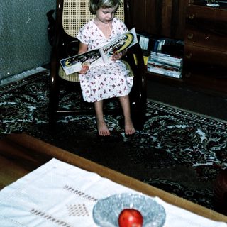 Young girl reading book in vintage chair.