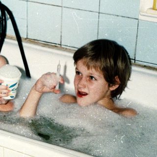 Two children playing in a bathtub with bubbles.