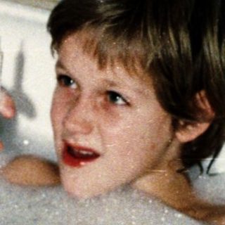 Two children playing in a bathtub with bubbles.