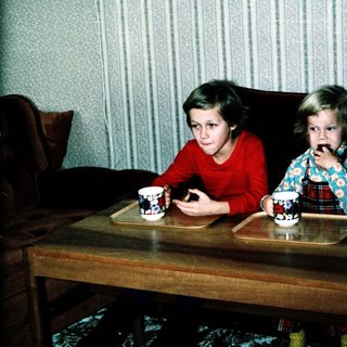 Two children drinking tea at a coffee table.