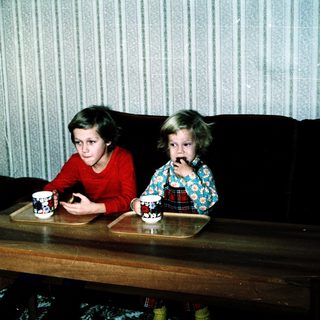 Two children drinking tea at a coffee table.