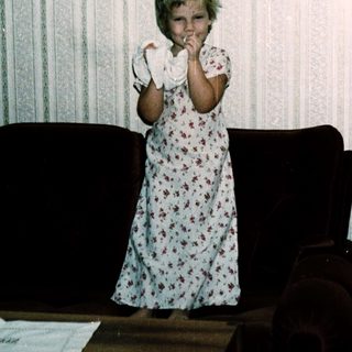Young girl in floral nightgown posing indoors.