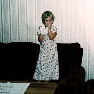 Young girl in floral nightgown posing indoors.