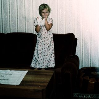 Young girl in floral nightgown posing indoors.