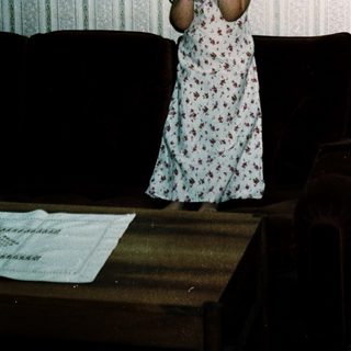 Young girl in floral nightgown posing indoors.
