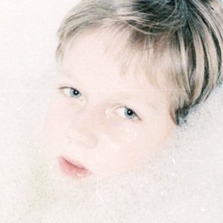 Child relaxing in a bathtub filled with bubbles.
