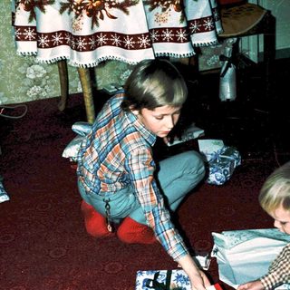 Two children wrapping holiday gifts indoors.