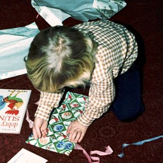 Person wrapping a gift on the floor.