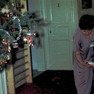 Family decorating Christmas tree indoors.