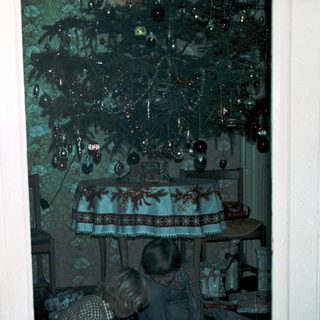 Two children playing video game indoors near festive decorations.
