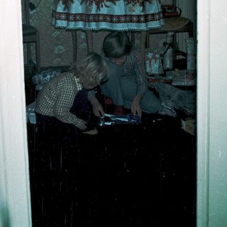 Two children playing video game indoors near festive decorations.