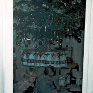 Two children playing with train set indoors.