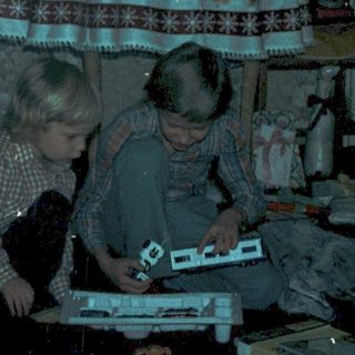 Two children playing with train set indoors.