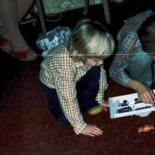 Two children opening and assembling toy cars.