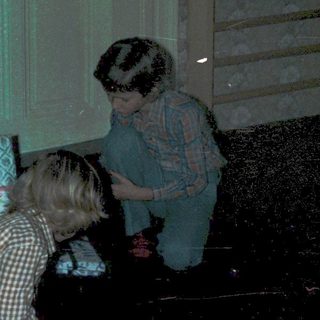Children opening Christmas presents under decorated tree.