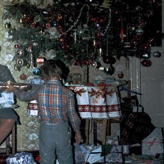 Woman wrapping holiday gifts with child nearby.