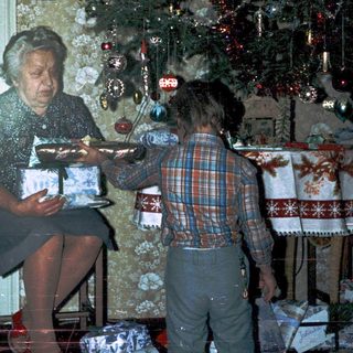 Woman wrapping holiday gifts with child nearby.